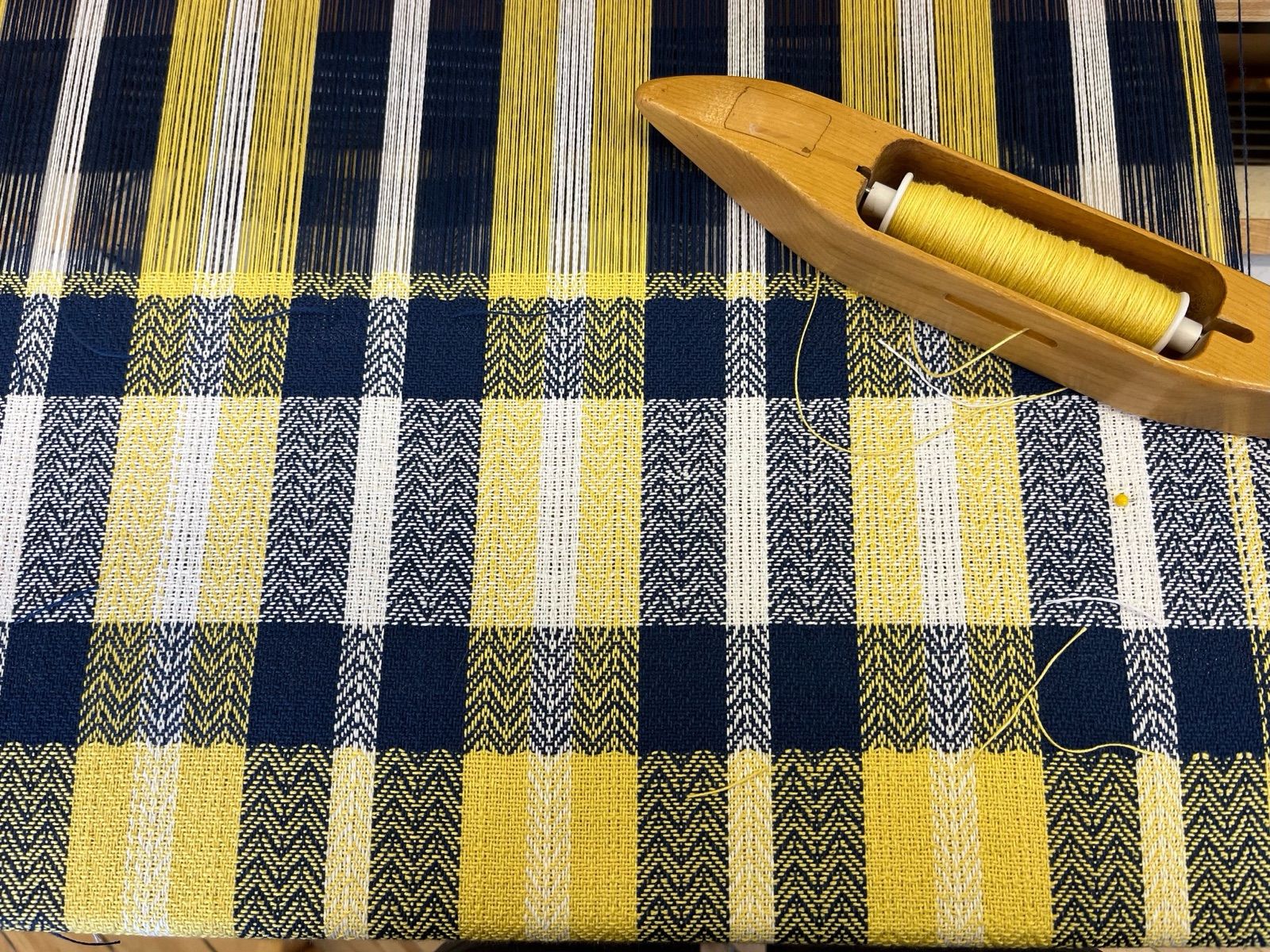 Plaid cloth with the shuttle still on it, woven by Ginny