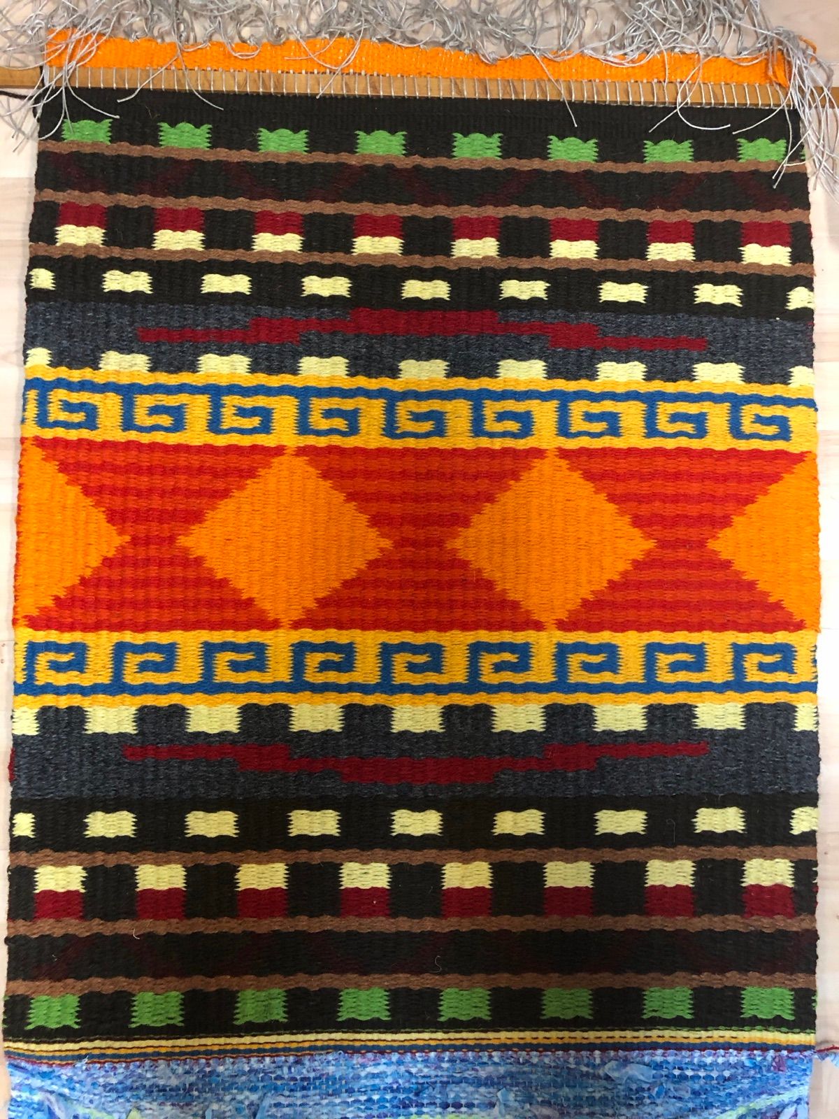 Handwoven rug in orange and black, woven by Mary